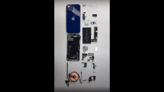 iPhone 12 desarmado mostrando módem Qualcomm X55 5G y batería de 1815 mAh